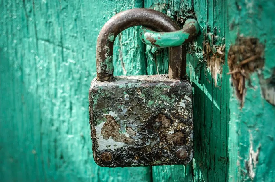 A weathered padlock on a green door